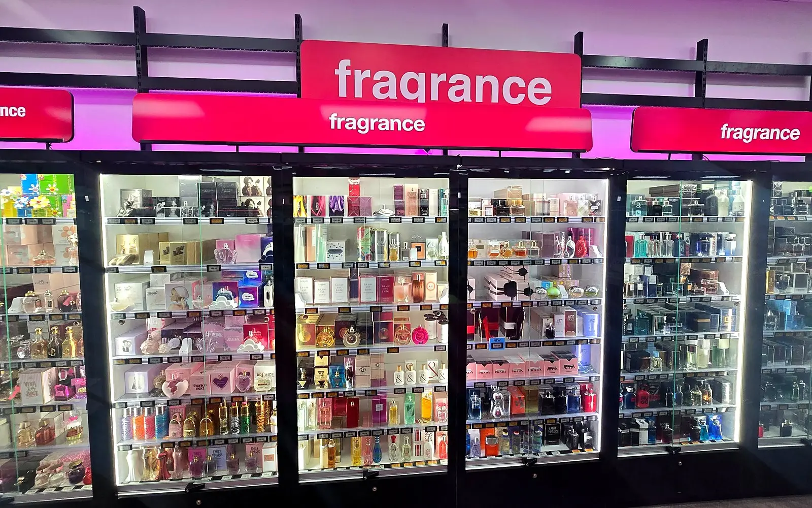 Glass fragrance cabinets lit in pink under a fragrance sign