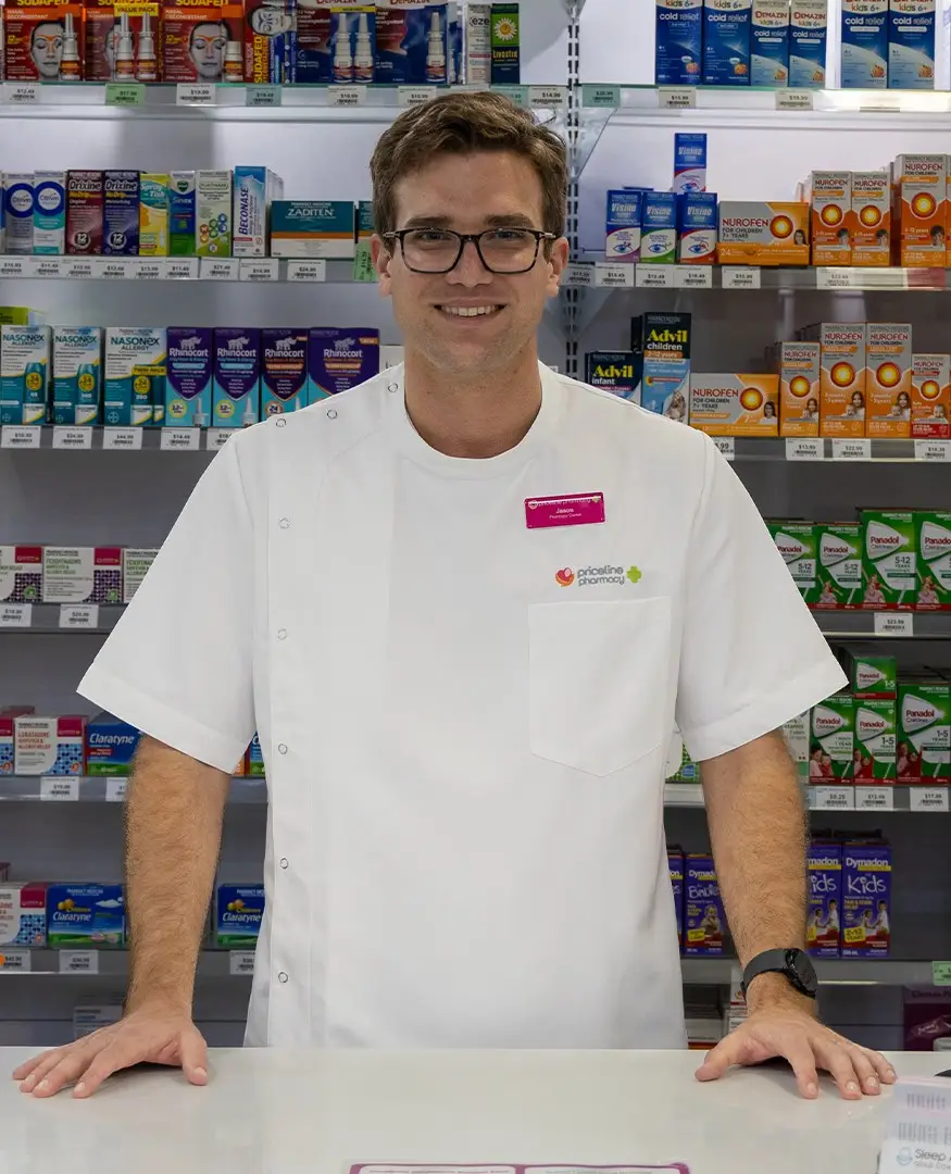 Pharmacist Jason Markey at the dispensary counter, in front of shelves of pharmacy medicines