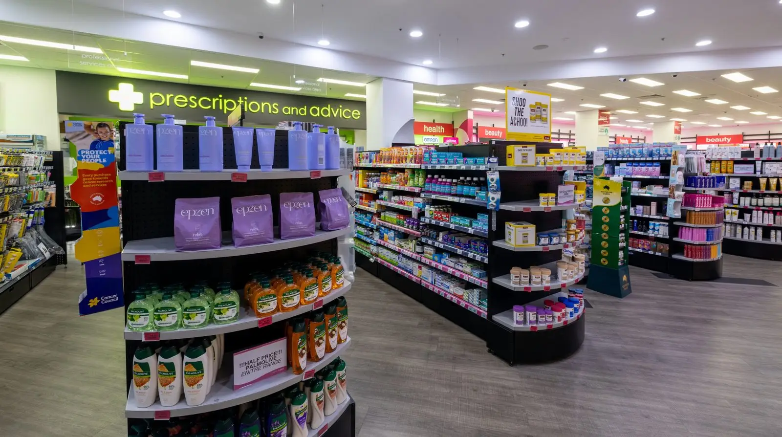 Aisles inside Priceline Pharmacy Pacific Fair, with the green prescriptions and advice sign at the back of the store