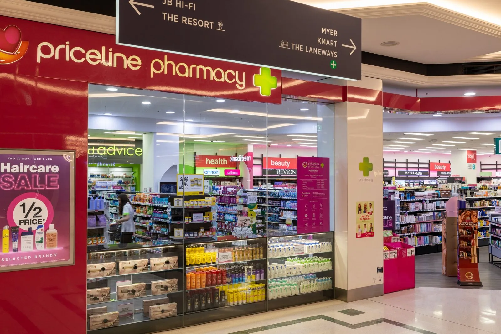 The red Priceline Pharmacy shopfront on the ground floor of Pacific Fair, below the centre signs to JB Hi-Fi, Myer and Kmart